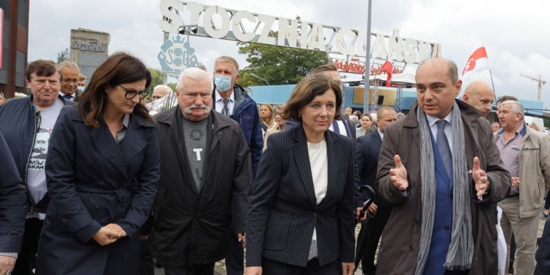 Lech Wałęsa, Věra Jourová i Aleksandra Dulkiewicz przechodzą przez bramę Stoczni Gdańskiej w 41 rocznicę podpisania Porozumień Sierpniowych
